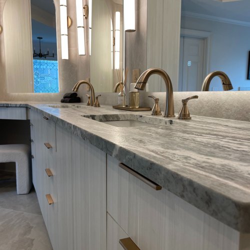 Grey bathroom countertops and cabinets with bronze accents
