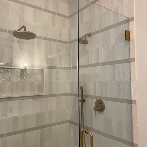 Neutral grey tiles in a shower with gold hardware