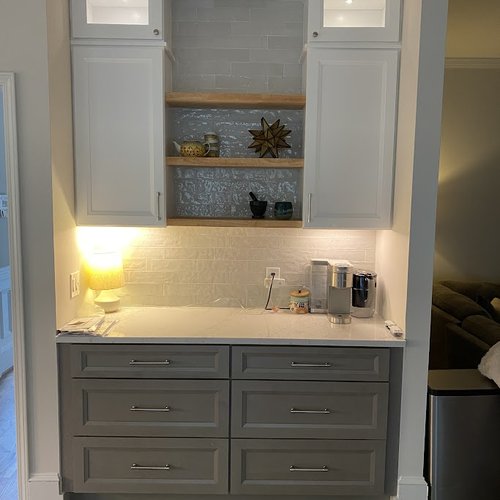 Glazed tile backsplash with grey cabinetry and wood shelves