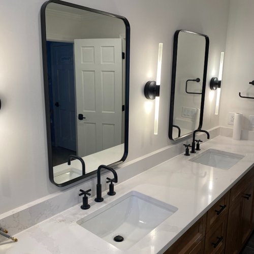 Black Mirrors in a modern bathroom with white marble countertops