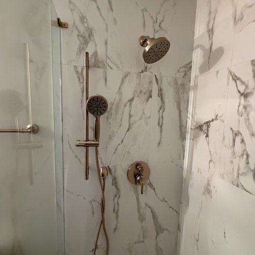White marble shower tile wall with gold hardware