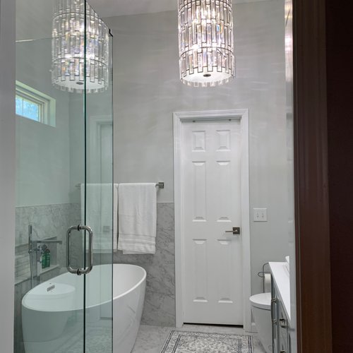 Bathroom with grey tile walls and a crystal chandelier