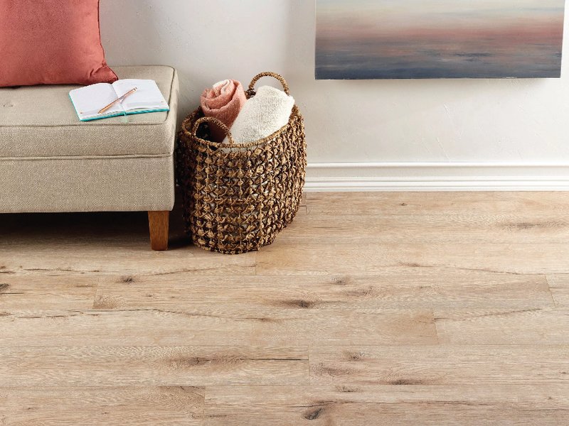 A room with a white wall and wooden floor, featuring water-resistant laminate flooring.